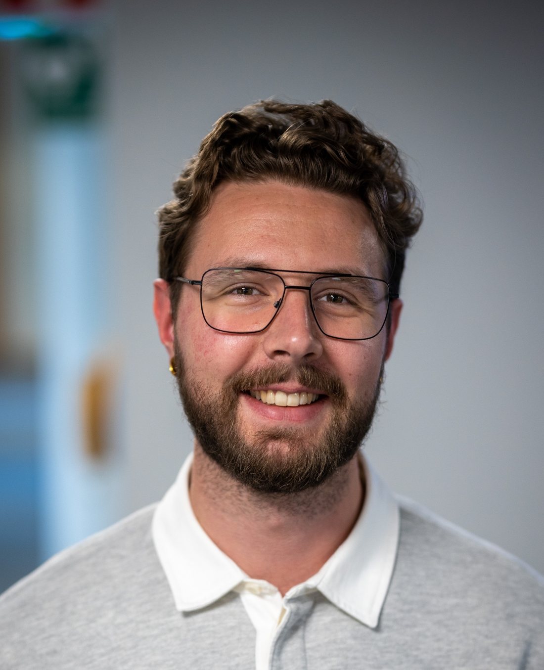 Caspian Lorén smiling, wearing glasses and a grey polo shirt
